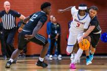 Bishop Gorman guard Ty Johnson (3) is fouled by Desert Pines guard Prince Davis (4) as forward ...